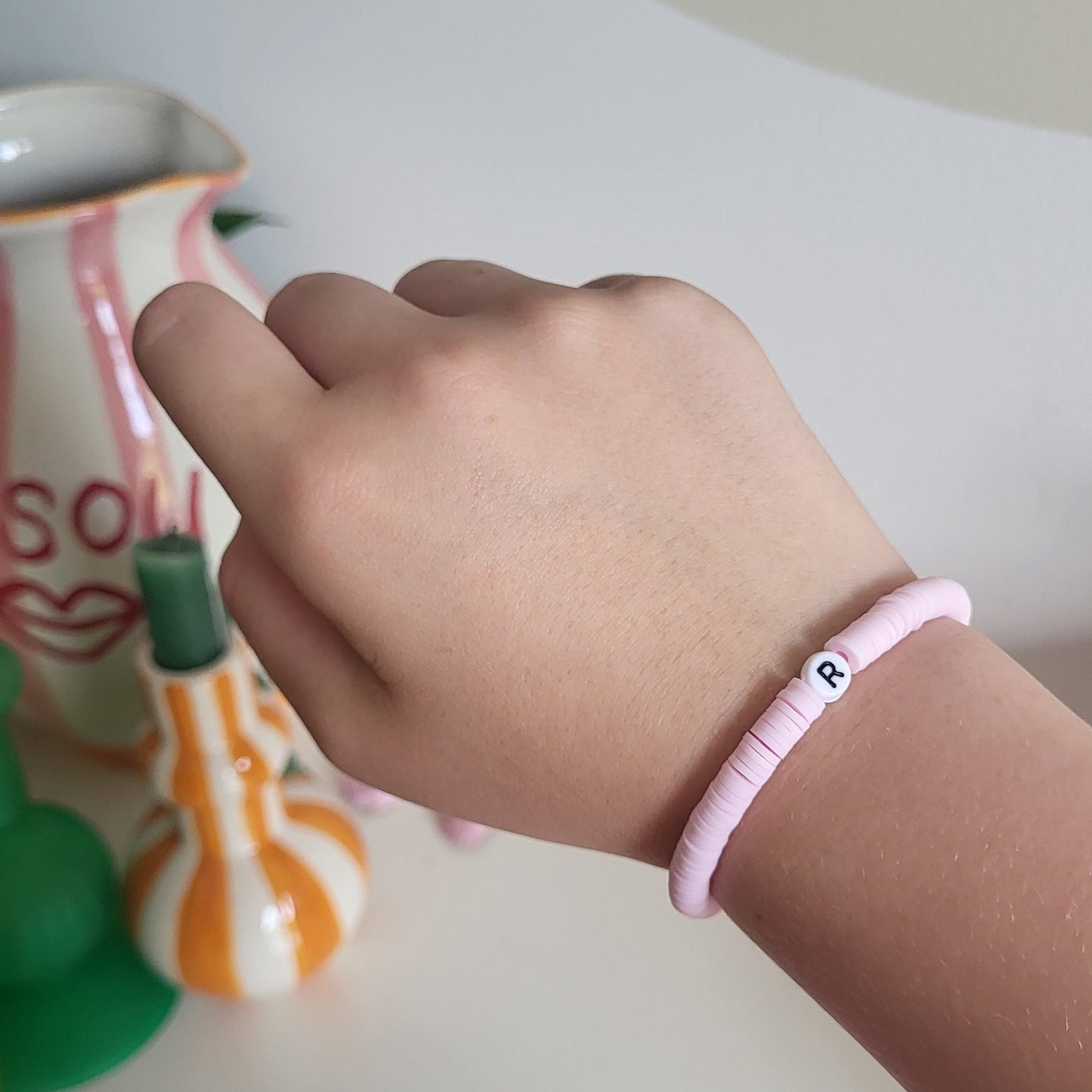 A light pink bracelet with "R" charm